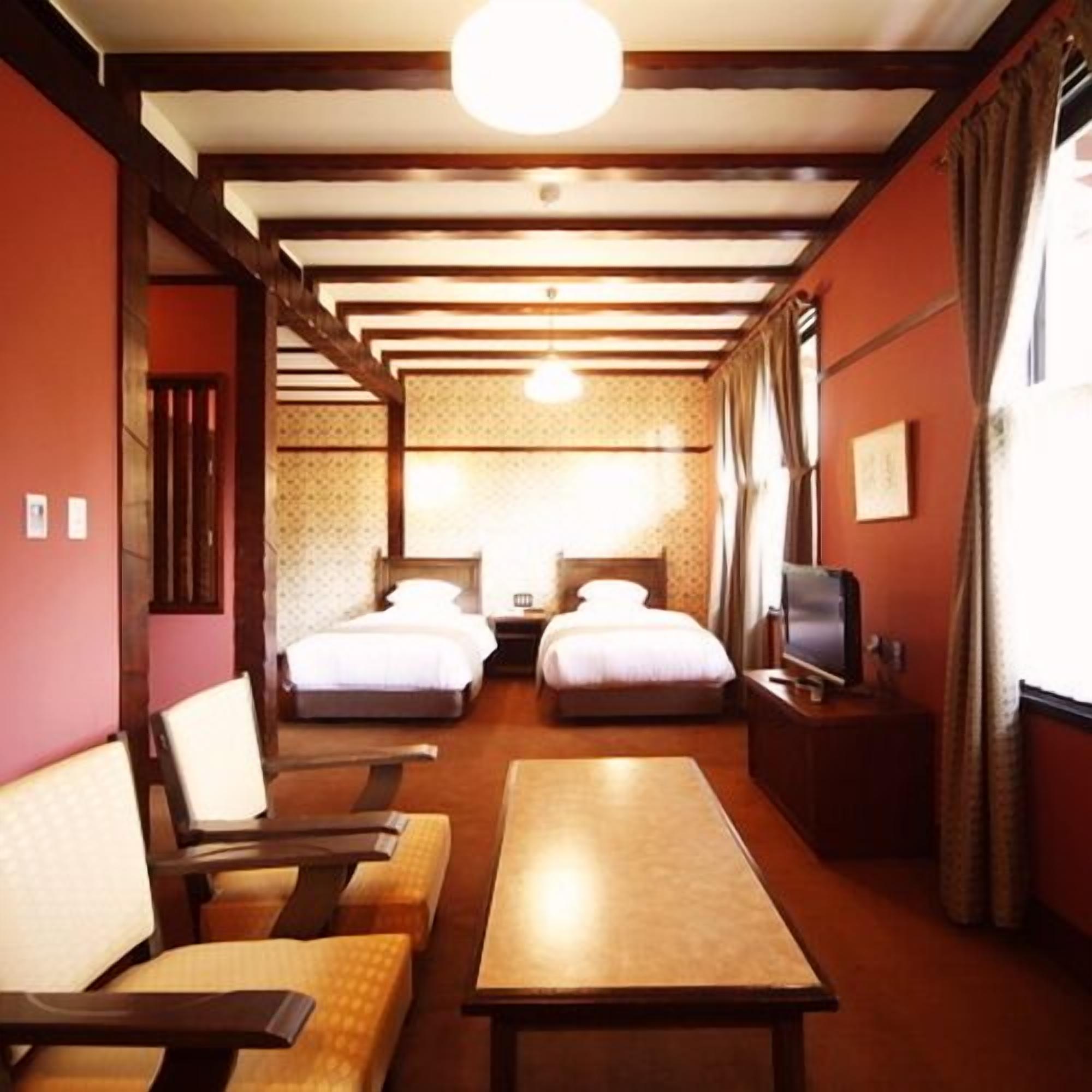 A hotel room with two beds, a sofa, a table, and a TV.