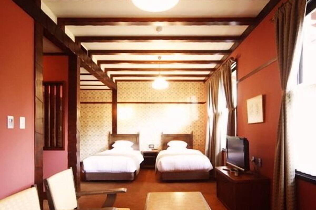 A hotel room with two beds, a sofa, a table, and a TV.
