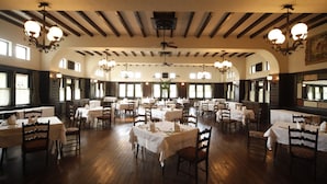 Un vaste espace dédié à la salle à manger, avec de nombreuses tables et chaises, un plancher en bois et de grandes fenêtres qui laissent entrer la lumière naturelle.