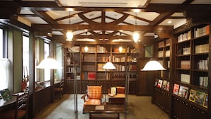 Une bibliothèque avec des étagères en bois, un fauteuil de lecture et deux lampadaires.