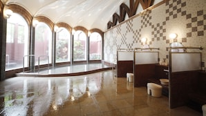 De vastes toilettes publiques dotées de plusieurs lavabos, d’un sol carrelé et d’un plafond haut avec des fenêtres en arc de cercle.