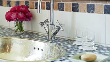 A bathroom with a sink, mirror, and a vase of flowers.