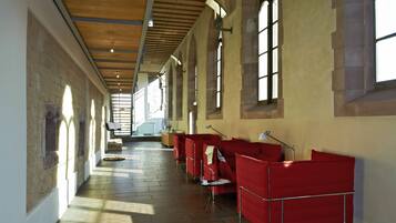A corridor with red seating areas, large windows, and a wooden ceiling.