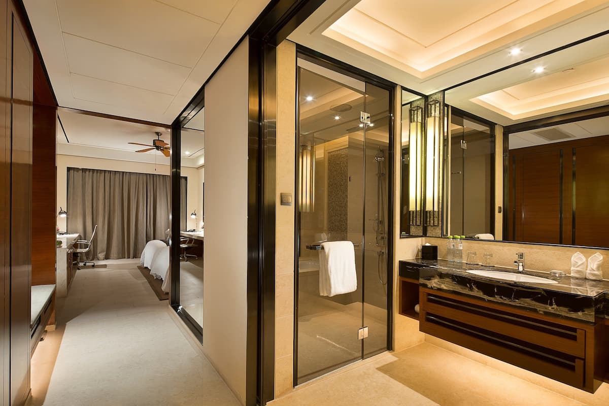 Un baño moderno con ducha envuelta en cristal, un espejo grande y encimera de mármol.