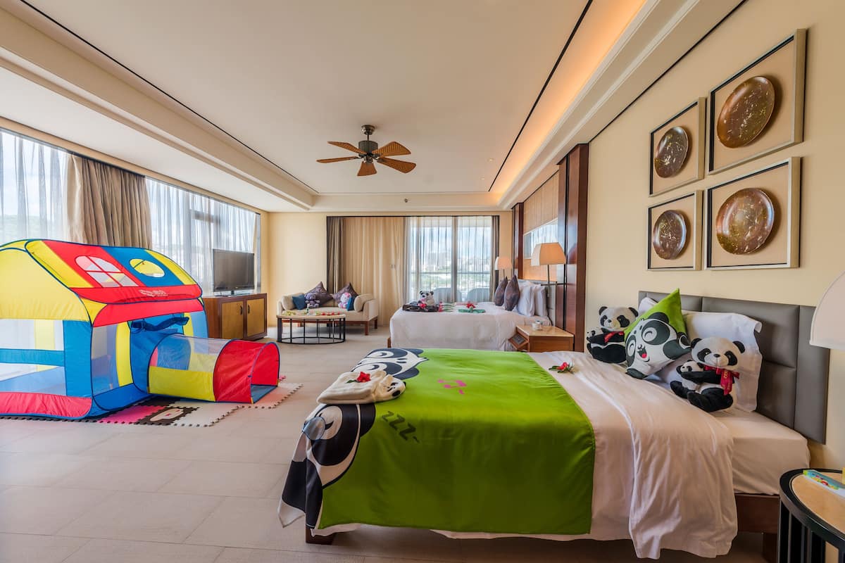 Una habitación de hotel con cama, una tienda de juegos, ventilador de techo y cuadros en la pared.