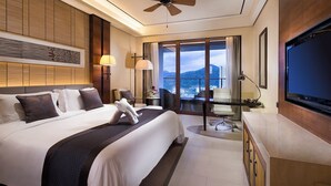 A hotel room with a large bed, a desk, a TV, and a balcony with a city view. - Crowne Plaza Sanya City Center by IHG (Sanya)