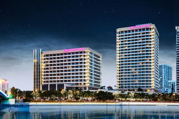 Un hôtel à étages, une enseigne bien visible et son reflet dans une étendue d’eau.