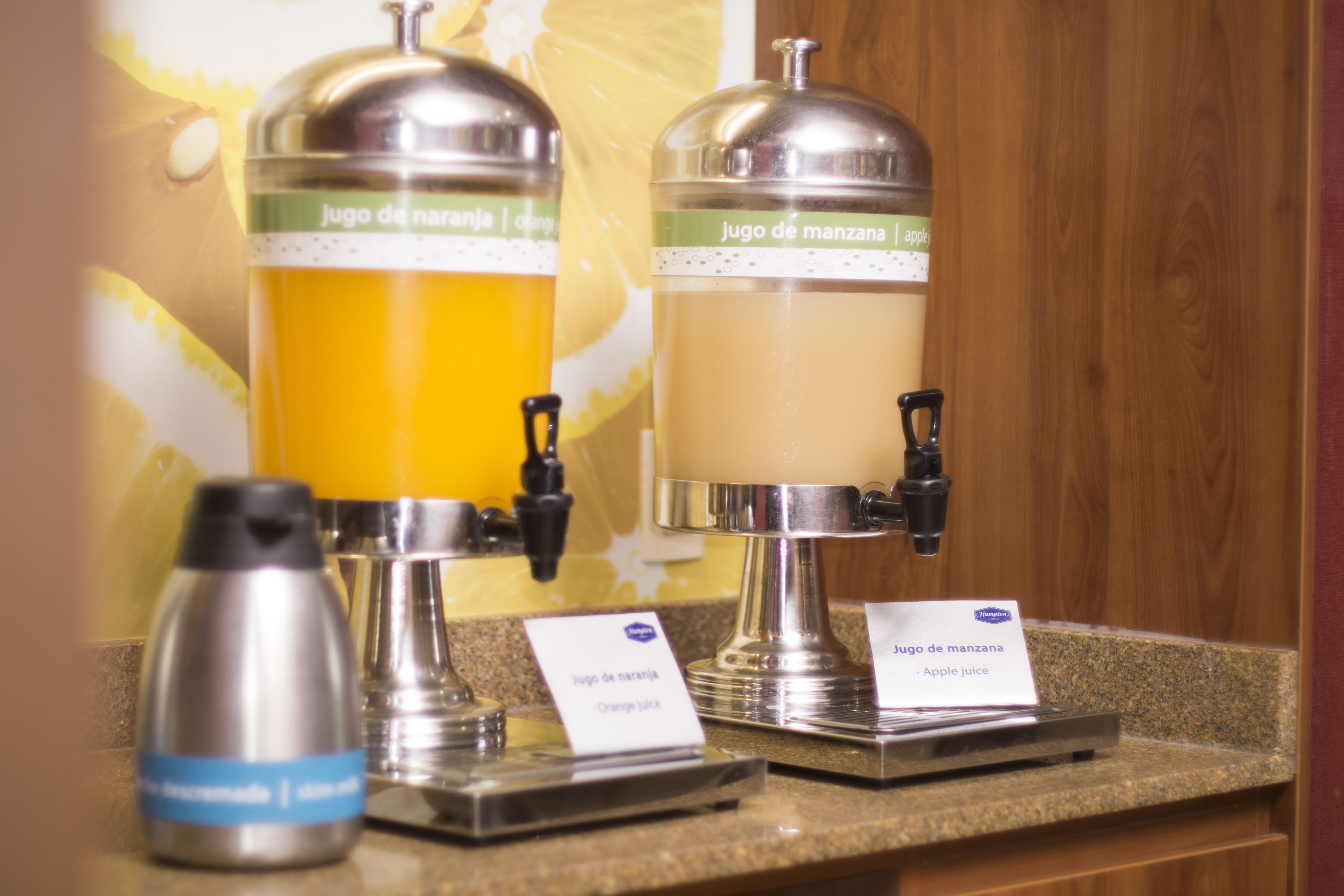 A juice dispenser with labels for orange and apple juice.