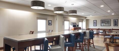 A spacious dining area with a long wooden table, multiple chairs, and pendant lighting.