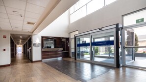 A spacious lobby with a wooden floor, a reception desk, and a glass door entrance. - Hampton Inn by Hilton San Juan del Rio (San Juan del Río)