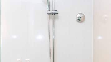 Une douche équipée d’un pommeau de douche à main, d’un robinet mural et de deux distributeurs de savon pour les mains de la marque Dove.