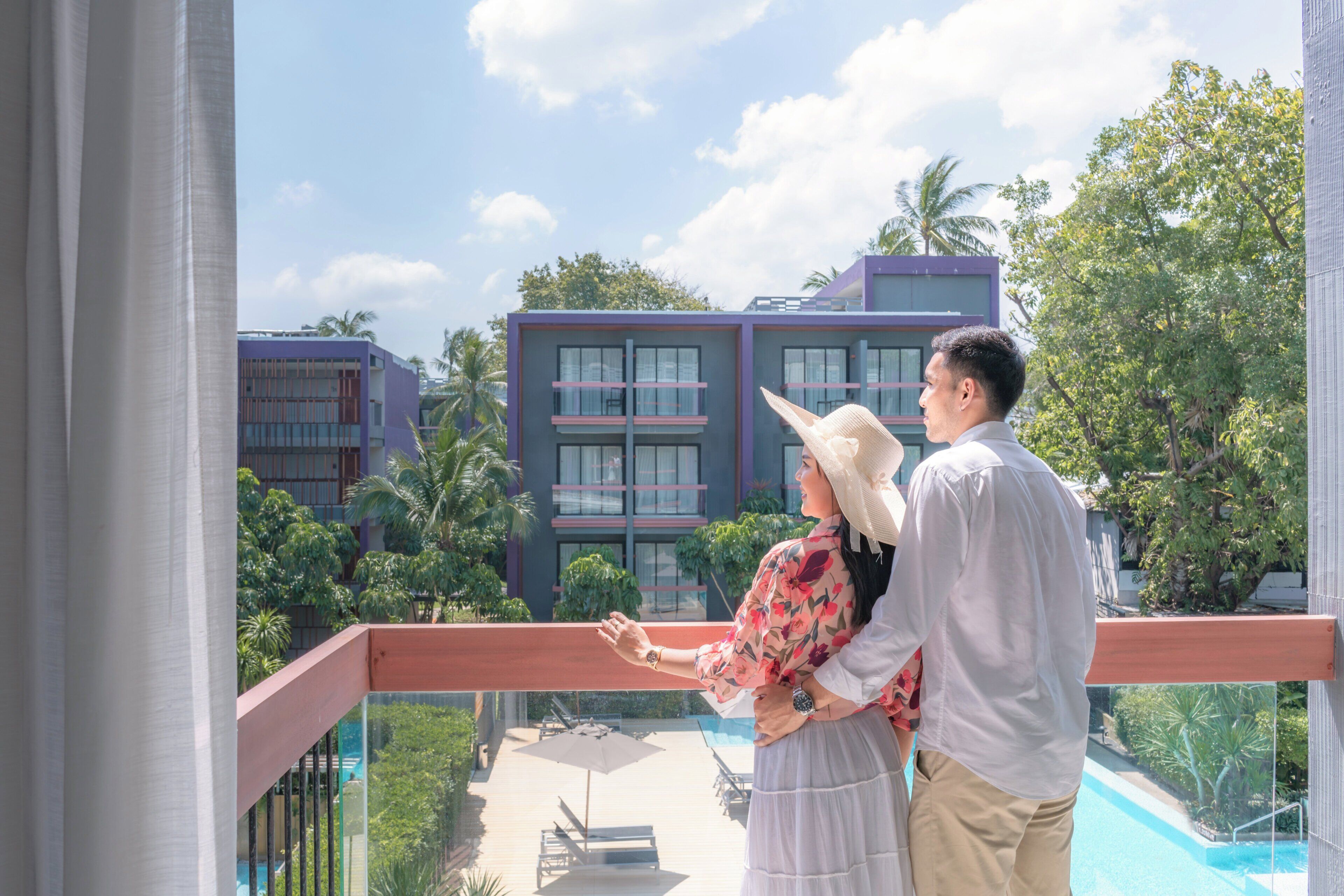 A balcony with a view of modern buildings and a swimming pool.