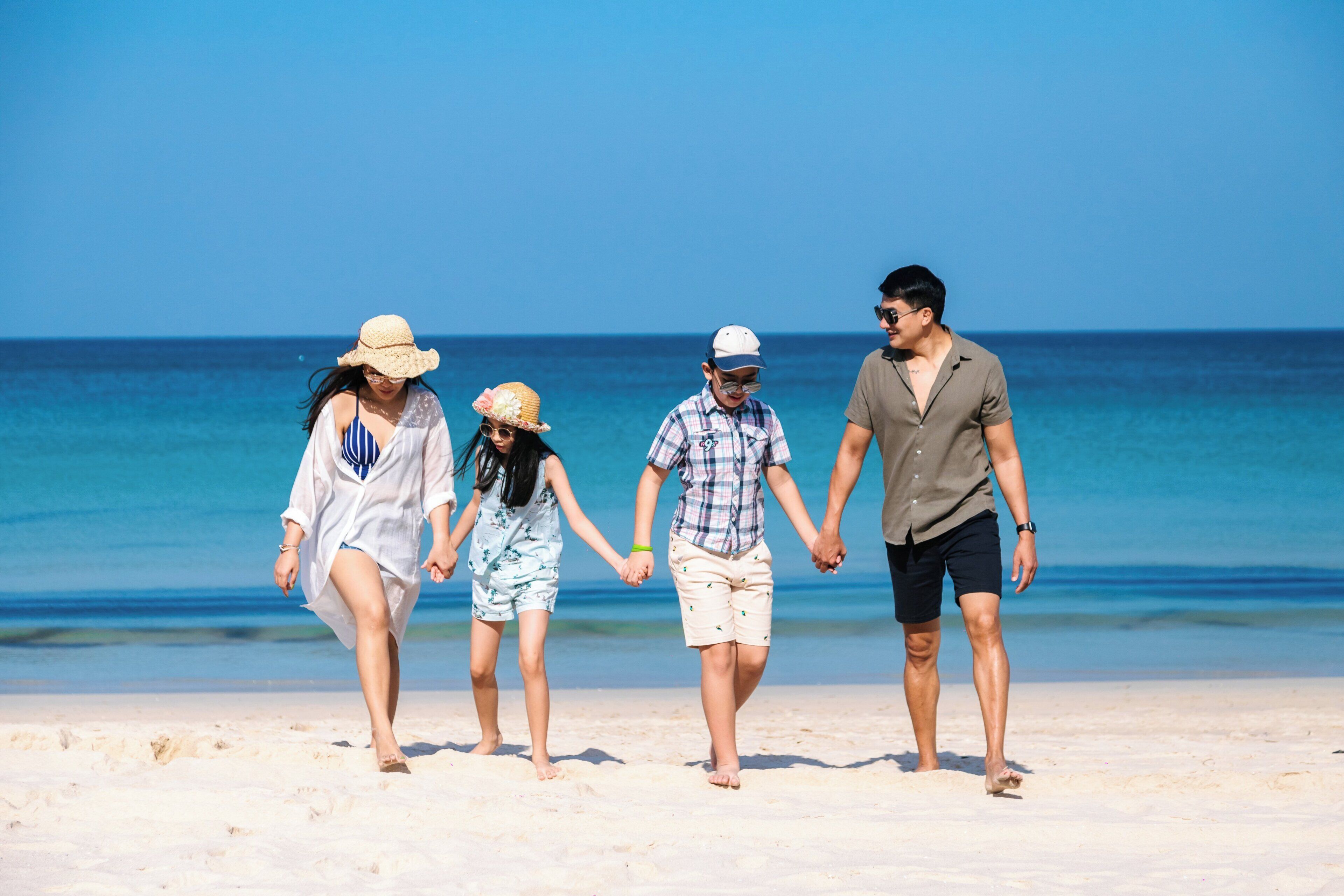 A family walking on a sandy beach with the ocean in the background.