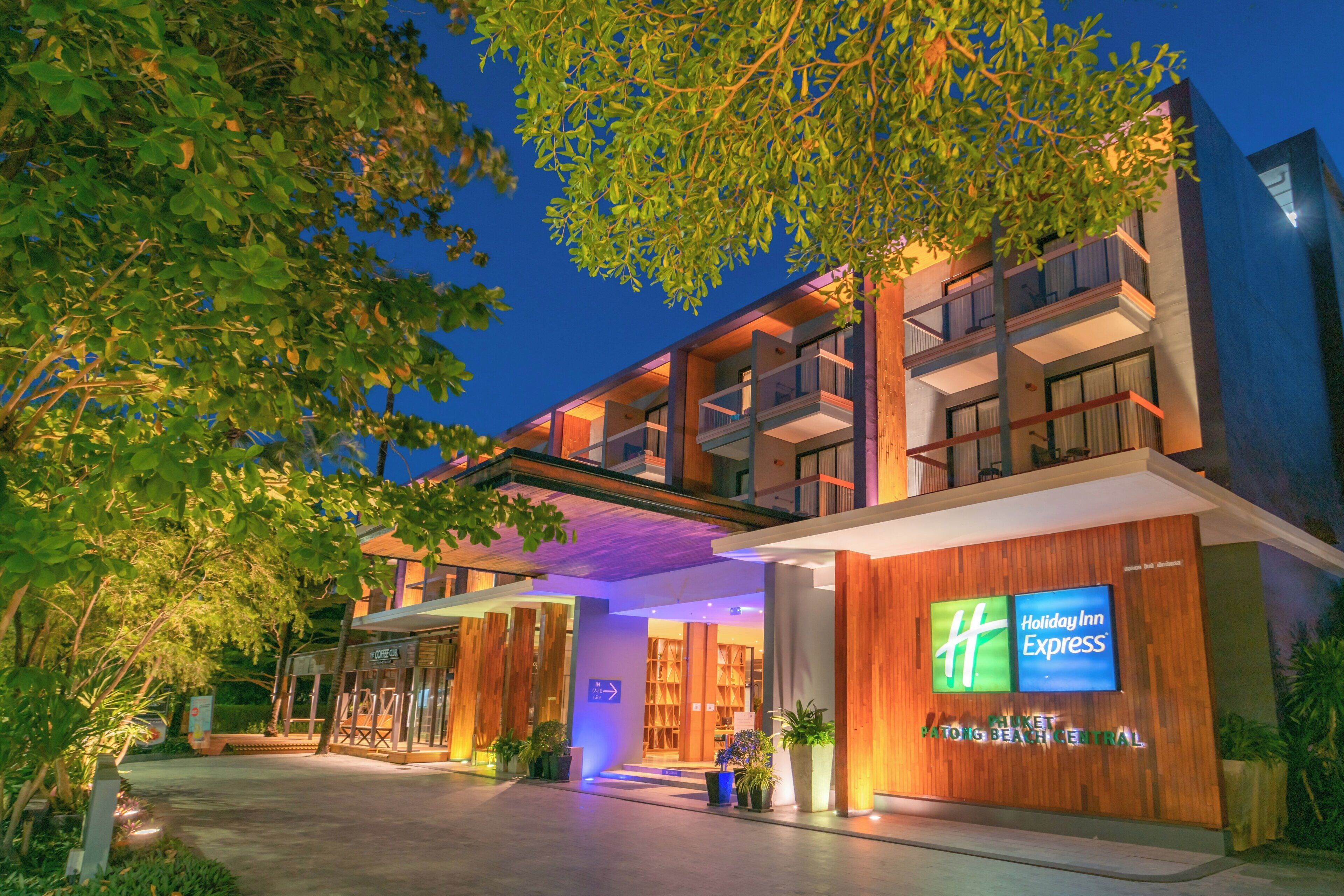 A modern hotel with a flat roof, multiple balconies, and a sign for Holiday Inn Express.