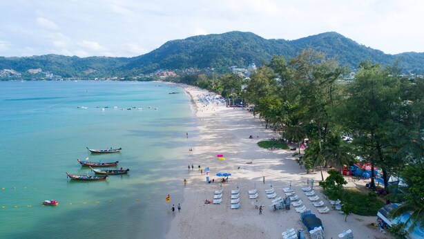 A beach with boats, beach chairs, umbrellas, and a mountainous backdrop. - Holiday Inn Express Phuket Patong Beach Central by IHG (Patong)