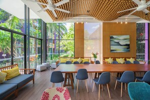 A modern meeting room with a large wooden table, blue chairs, and a sofa with yellow cushions. - Holiday Inn Express Phuket Patong Beach Central by IHG (Patong)