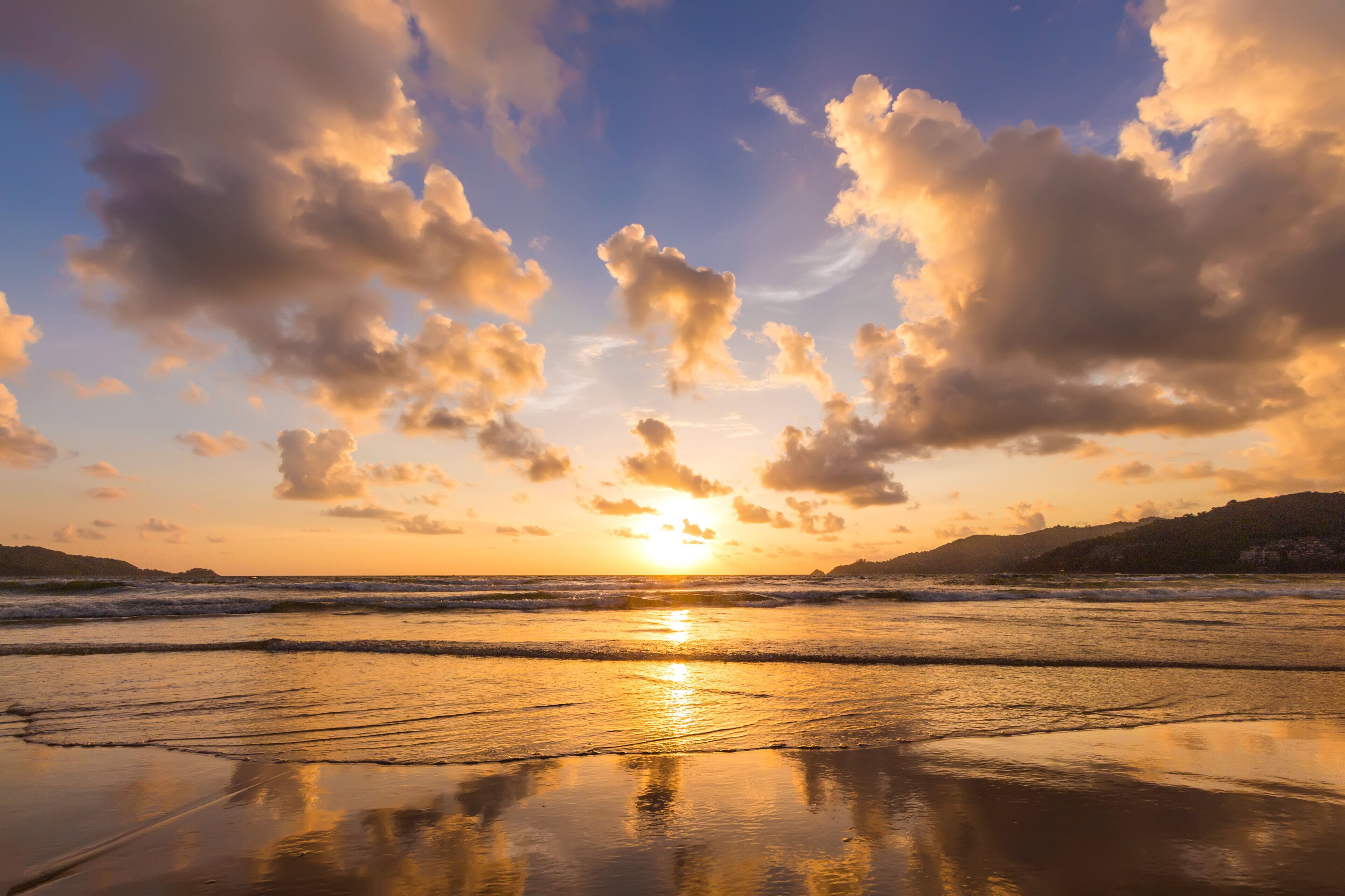 A beach with waves and a sunset.