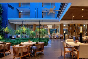 A modern indoor space with multiple seating areas, including round tables and chairs, surrounded by greenery and plants. - Holiday Inn Express Phuket Patong Beach Central by IHG (Patong)