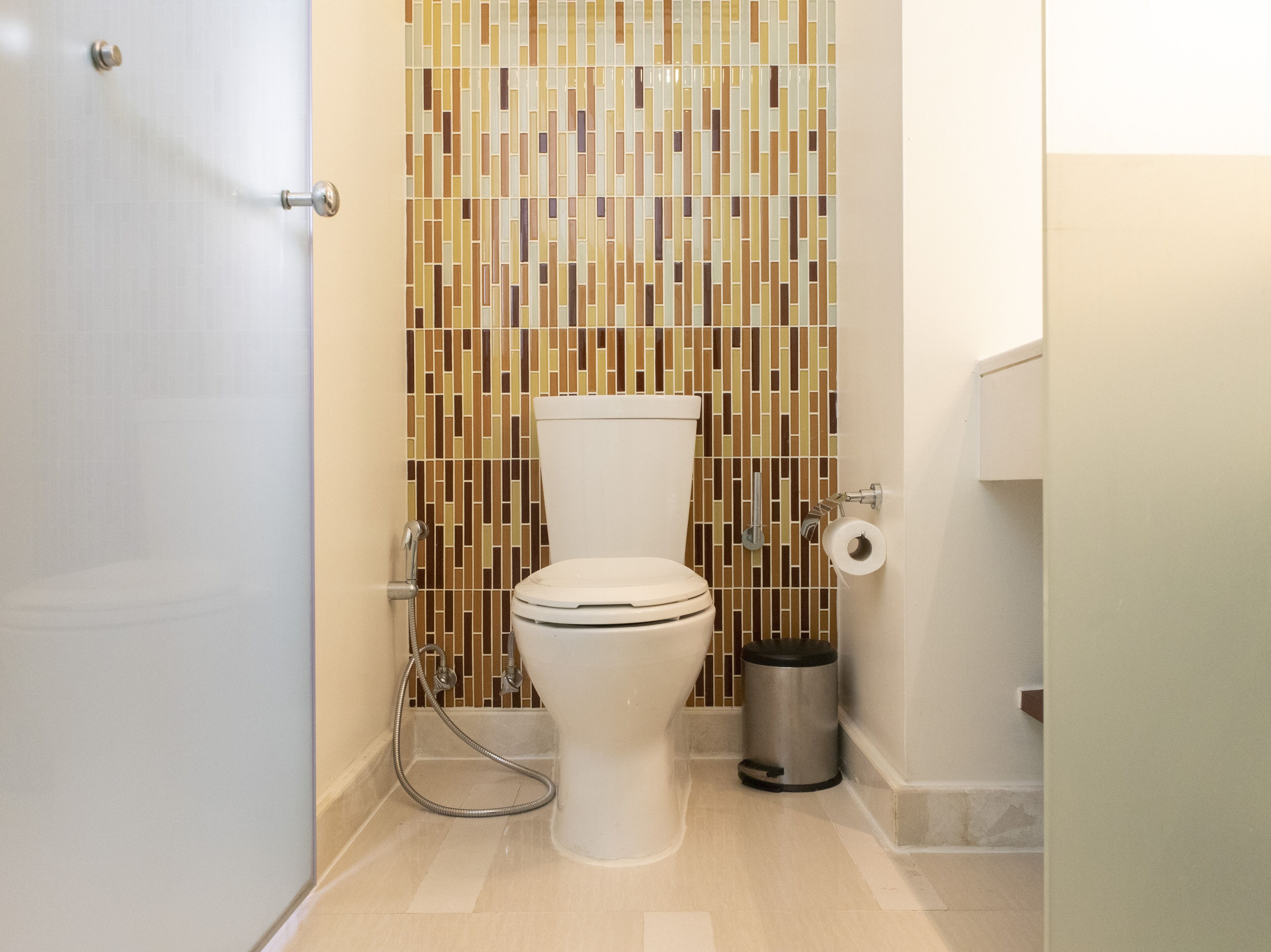 A bathroom with a toilet, a shower, and a trash can.