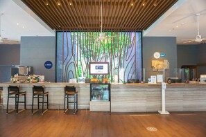 A modern reception area with a wooden ceiling, a digital display, and a bar with stools. - Holiday Inn Express Phuket Patong Beach Central by IHG (Patong)