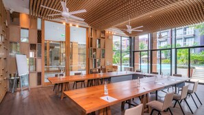 A modern conference room with wooden tables and chairs, large windows, and ceiling fans. - Holiday Inn Express Phuket Patong Beach Central by IHG (Patong)