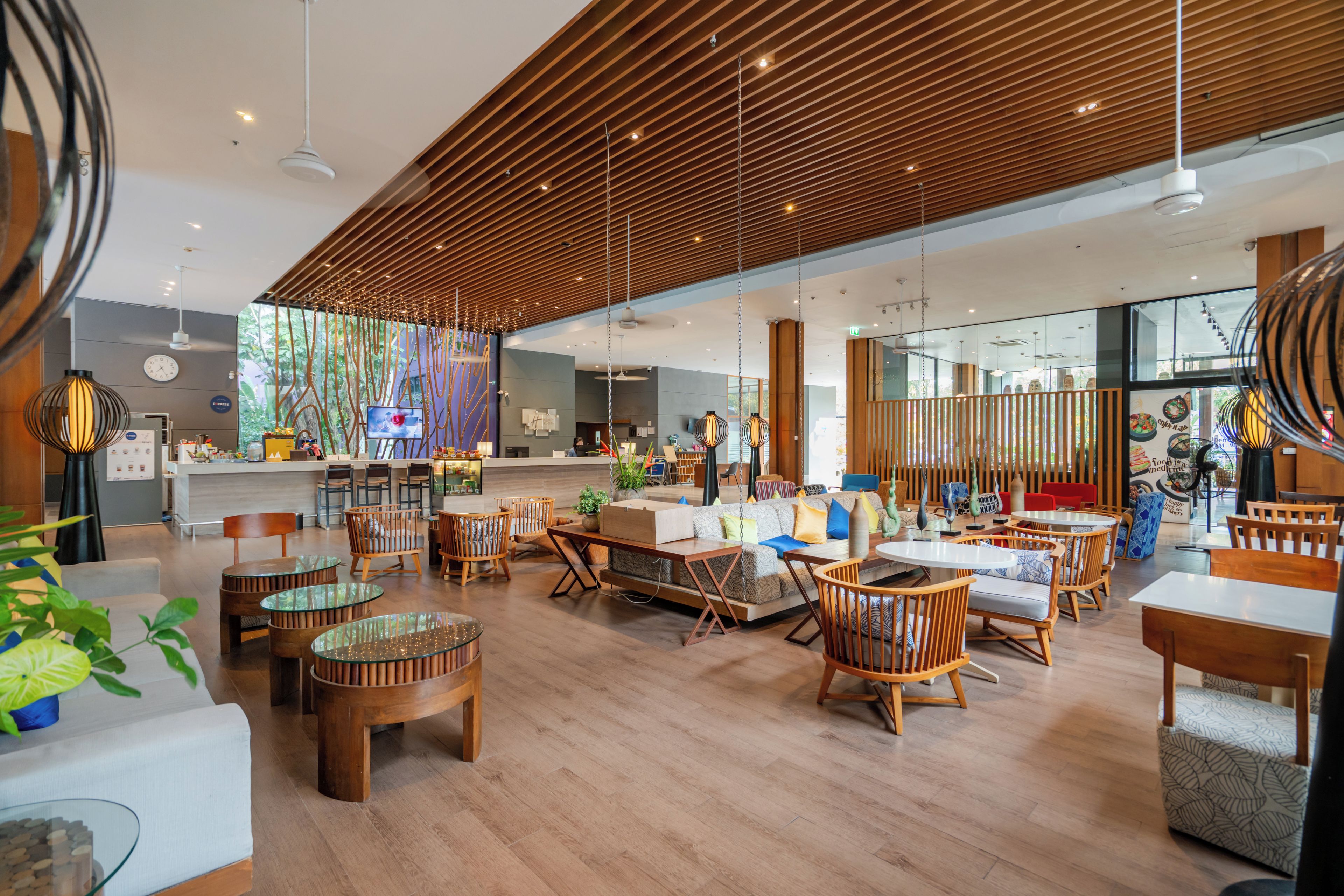 A modern interior with wooden slatted ceilings, glass partitions, and a variety of seating arrangements including tables and chairs.