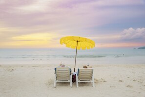 Due lettini da spiaggia con un ombrellone giallo rivolti verso il mare.