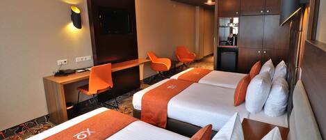 A hotel room with two beds, a desk, a TV, and a seating area.
