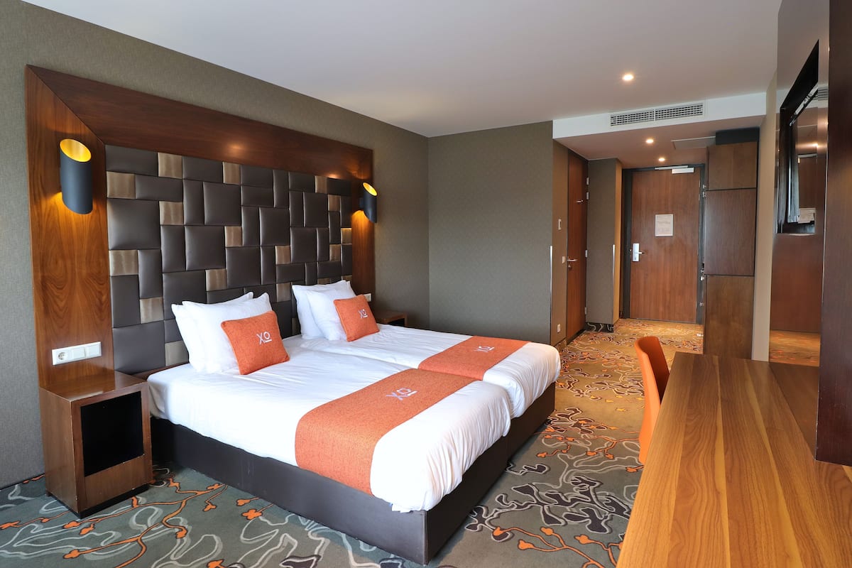 Une chambre d’hôtel avec un grand lit, une tête de lit en bois, une table de chevet et un bureau en bois.