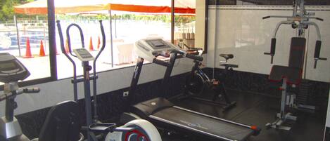 Un gimnasio con cintas de correr, bicicletas estáticas y máquinas de pesas.
