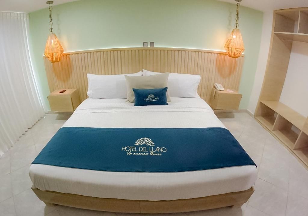 A hotel room with a bed, two bedside tables, and a headboard.