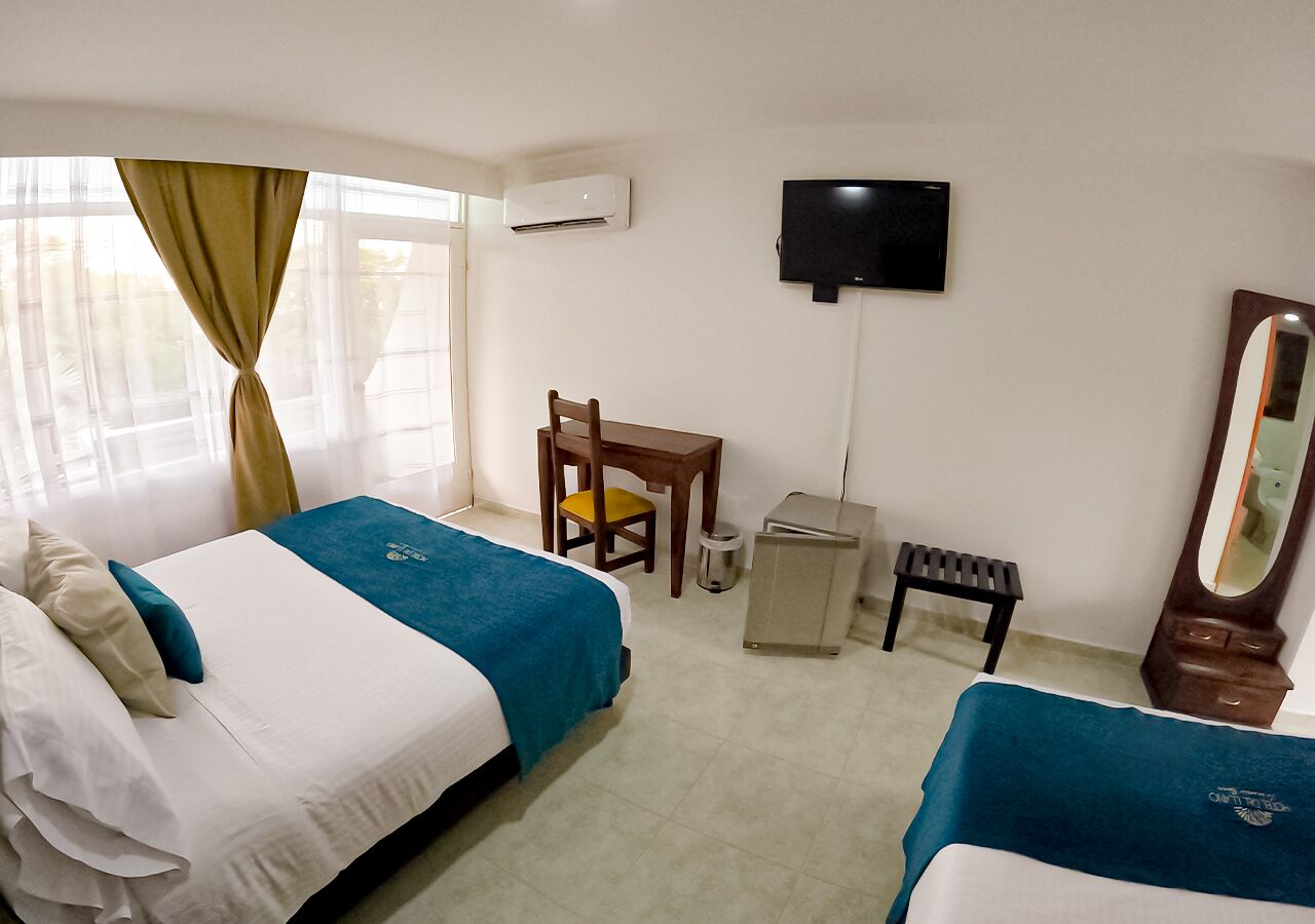 Ein Hotelzimmer mit zwei Betten, einem Schreibtisch, einem Stuhl, einem Fernseher, einem Spiegel und einer Klimaanlage.