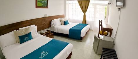 A hotel room with two beds, a desk, and a TV.