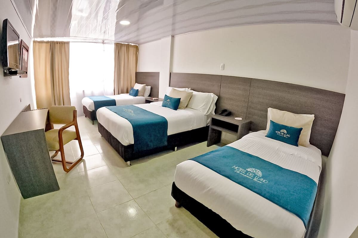 Une chambre d’hôtel avec deux lits, un bureau et une chaise.