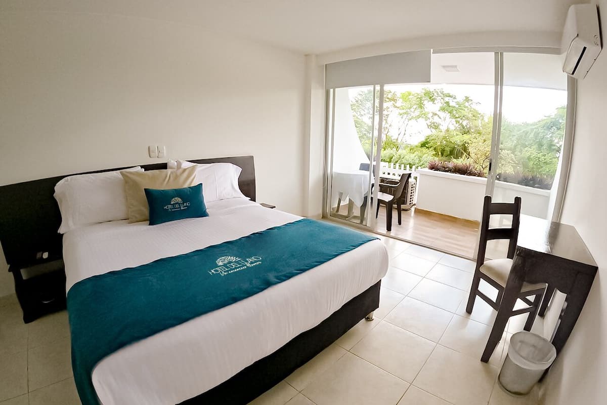 Une chambre d’hôtel comprenant un lit, un bureau, une chaise et un balcon avec une table et des chaises.