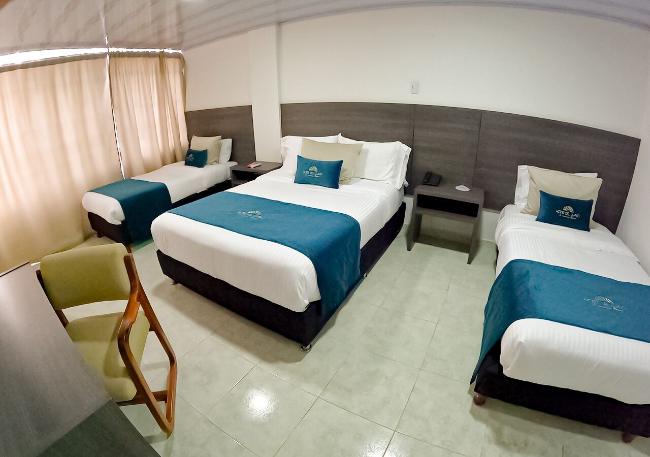 A hotel room with three beds, a desk, and a chair.