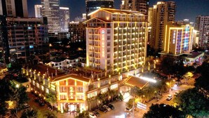 A multi-story hotel with a prominent entrance, surrounded by other buildings and palm trees. - Sanya Yi Yuan Xuan Yu Hotel (Sanya)