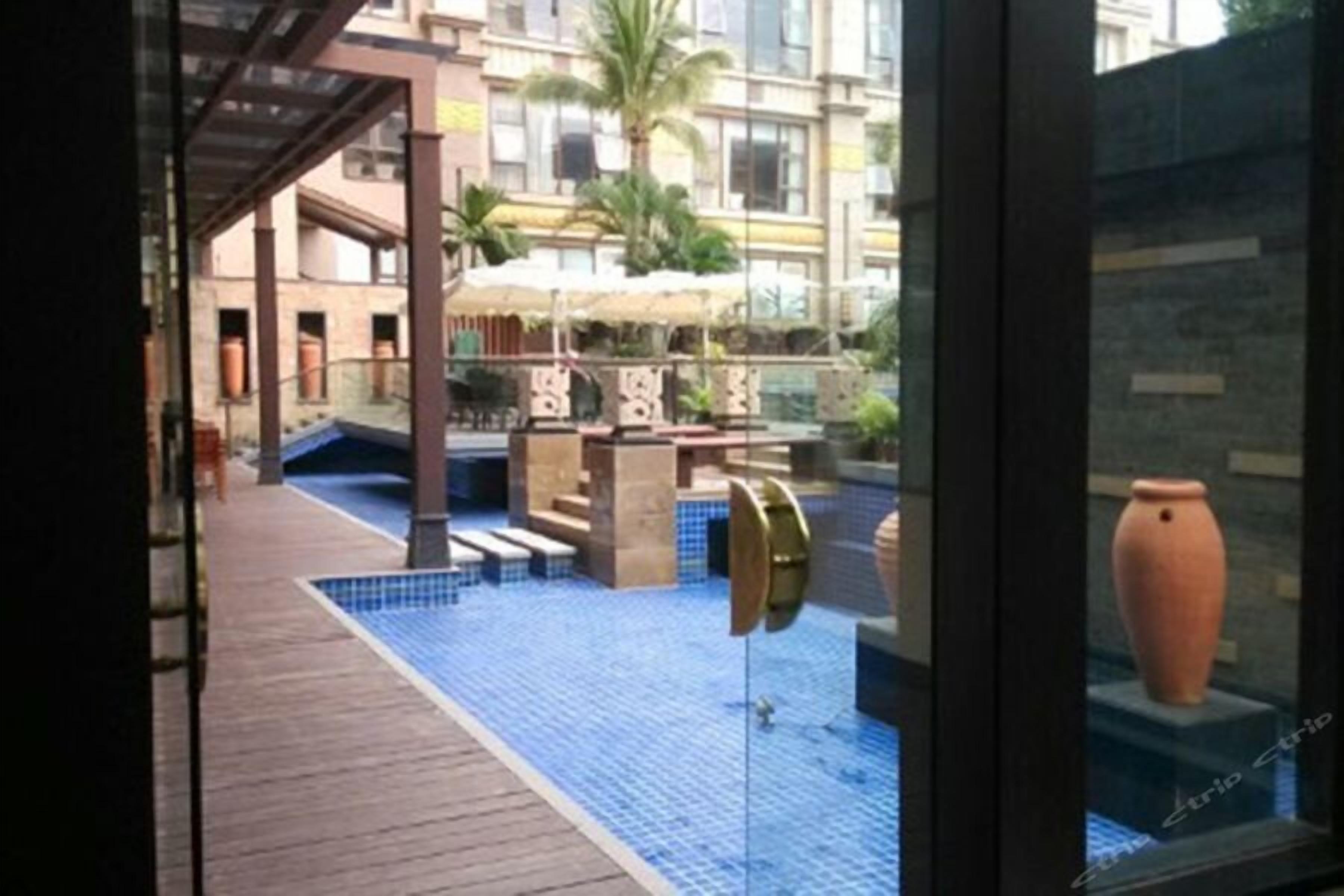 A pool area with a tiled floor, a pergola, and a large vase on display.