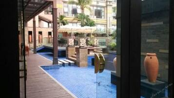 A pool area with a tiled floor, a pergola, and a large vase on display.