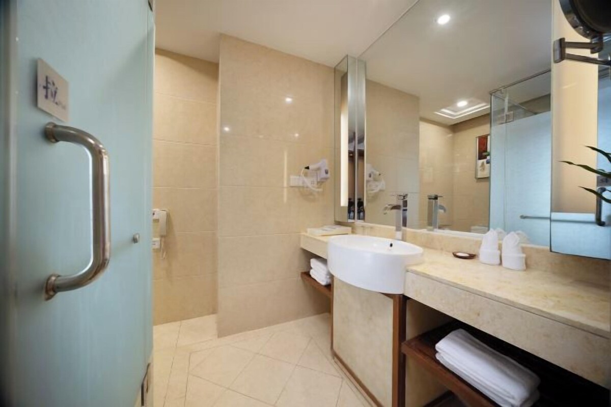 A modern bathroom with a large mirror, a sink, and a shower area.