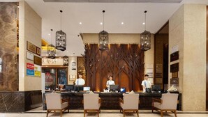 A hotel reception area with three reception desks, a decorative wall with tree motifs, and hanging light fixtures. - Sanya Yi Yuan Xuan Yu Hotel (Sanya)