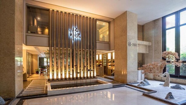 A modern hotel lobby with a central vertical light feature, a reception desk, and a decorative sculpture. - Sanya Yi Yuan Xuan Yu Hotel (Sanya)