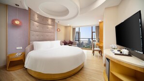 A modern hotel room with a large bed, a TV, a desk, and a balcony with a city view. - Sanya Yi Yuan Xuan Yu Hotel (Sanya)