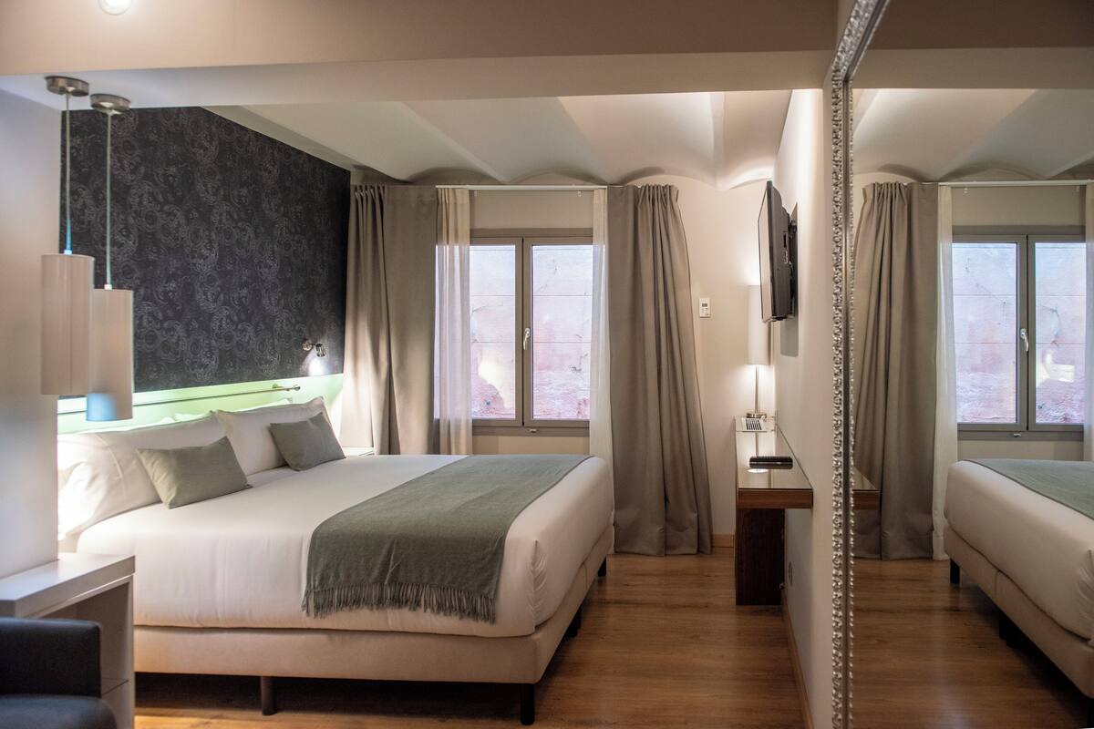 A modern hotel room with a large bed, a desk, and a TV.