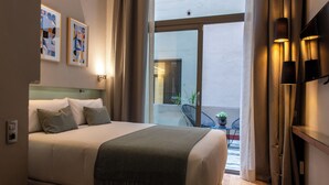 A modern hotel room with a large bed, a view to the outside, and a small balcony area. - Vasanta Hotel (Barcelona)