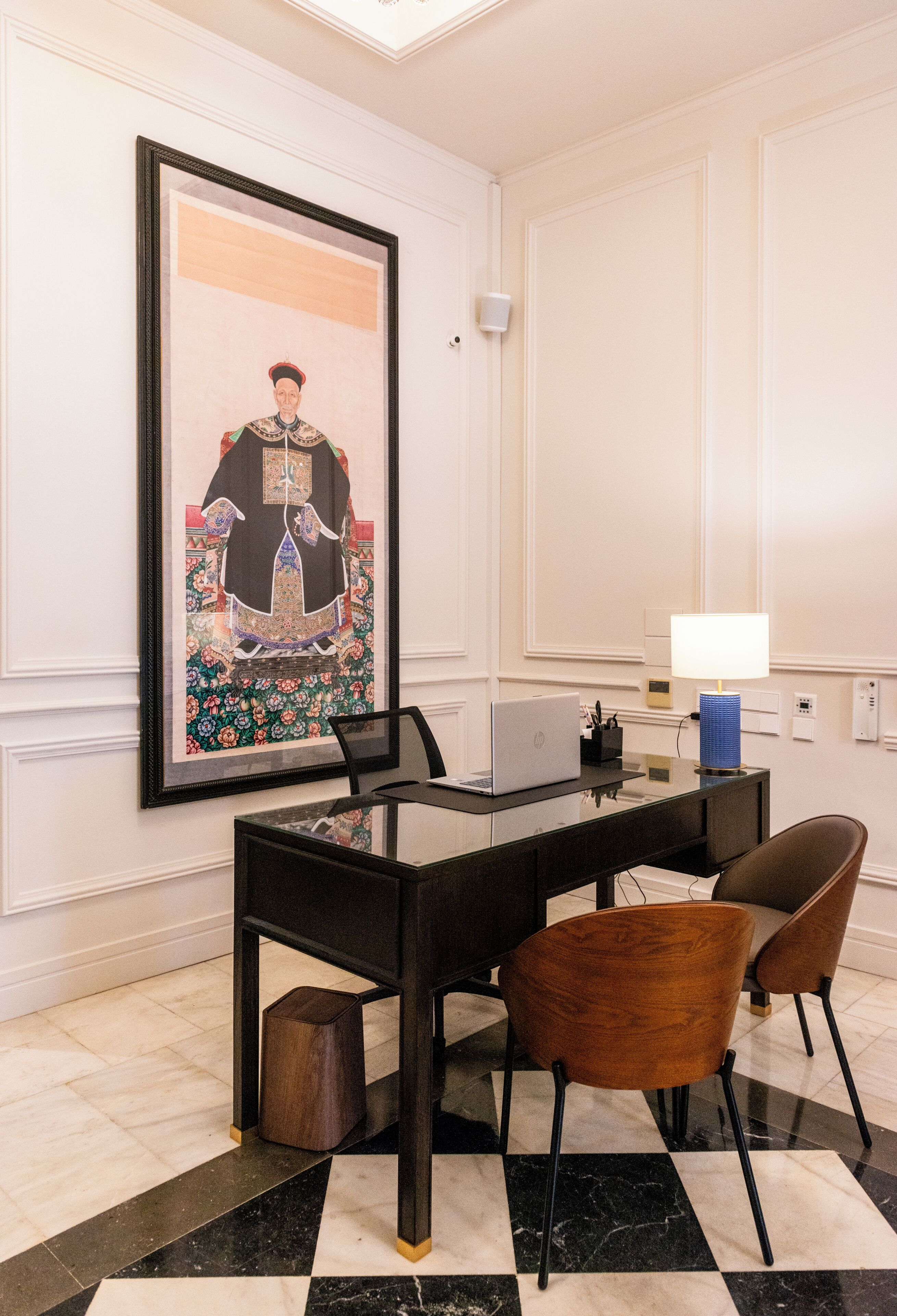 Habitación de hotel con una mesa de comedor, sillas, una computadora portátil, una obra de arte enmarcada y una lámpara.