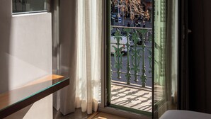 A hotel room with a large window, a bed, a bedside table, and a view of the cityscape. - Vasanta Hotel (Barcelona)