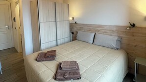 A bedroom with a wooden ceiling, a bed with a beige quilt, and a wardrobe. - Homely - Malpensa & Fiere Milano (Cardano al Campo)