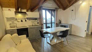 A spacious loft with a dining area, kitchen, and a white sofa. - Homely - Malpensa & Fiere Milano (Cardano al Campo)