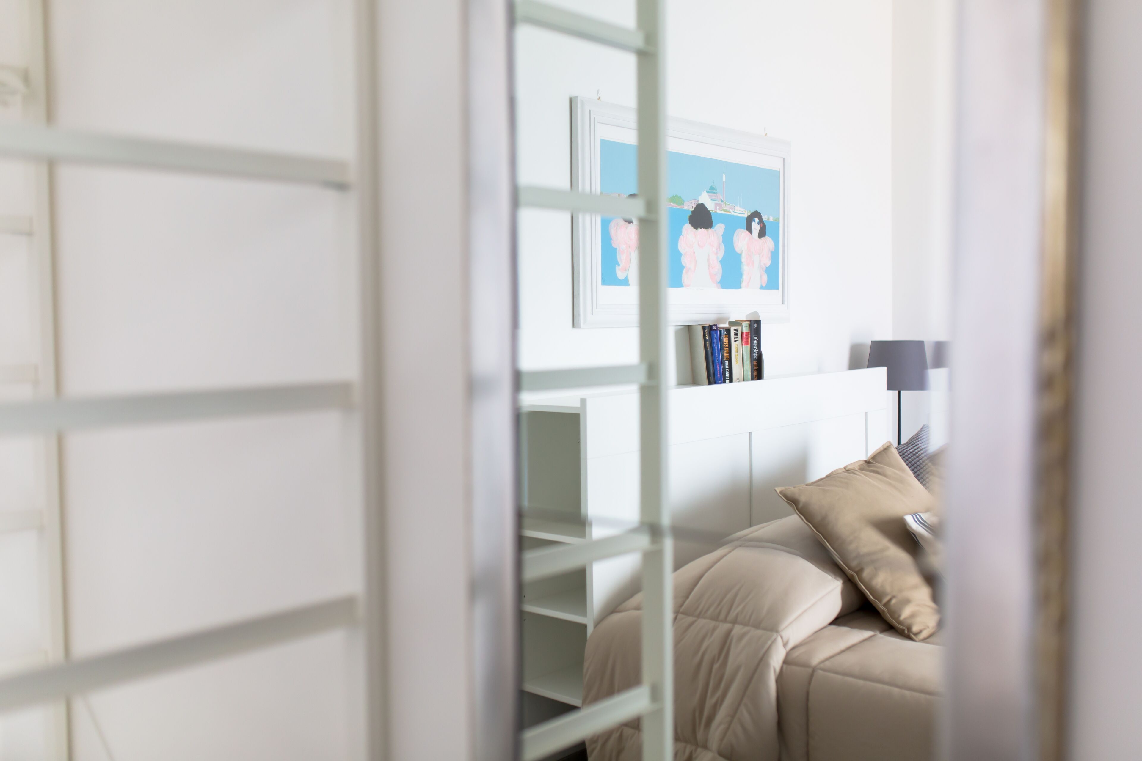 Une chambre avec un lit superposé, une table de chevet, une lampe et un tableau encadré au mur.